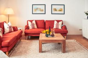a living room with two red couches and a coffee table at Ferienhaus Fiete XXL auf Rügen - Doppelferienhaus für 16 Personen in Sagard