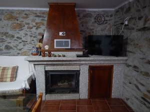a living room with a fireplace and a flat screen tv at Casa da Pracica, Serapicos in Vale de Frades