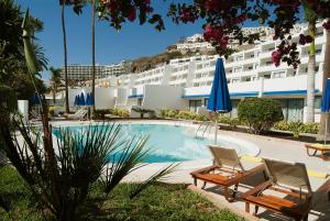 a swimming pool with two chairs and a hotel at El Greco in Puerto Rico de Gran Canaria