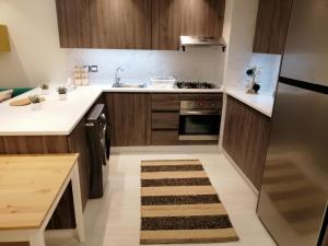 Elle comprend une petite cuisine avec des placards en bois et un évier. dans l'établissement Amazing Studio in DAMAC, à Amman