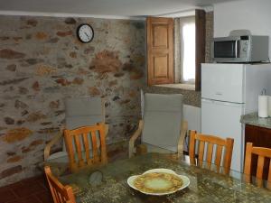 a kitchen with a table and chairs and a clock on the wall at Casa da Pracica, Serapicos in Vale de Frades