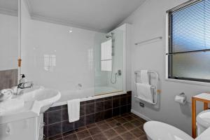 a white bathroom with two sinks and a shower at Remarkable Views 3 bedroom - lake & mountain views in Queenstown