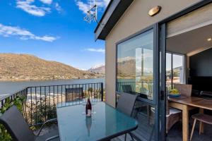 a balcony with a glass table and a view of the water at Remarkable Views 3 bedroom - lake & mountain views in Queenstown