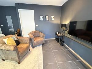 a living room with a tv and a couch and a chair at In de Witte Dame Hotel Bar Kitchen Apartments in Grubbenvorst +89 photos