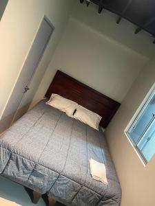 1 dormitorio con 1 cama con cabecero de madera y ventana en Hostal Low Cost, en Santiago