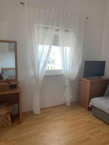 Schlafzimmer mit einem Fenster mit weißen Vorhängen und einem Spiegel in der Unterkunft Apartment Tihana in Vir