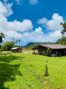 a house in a field with a green yard at Huahine Serenity Cottage in Maroe