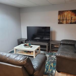 a living room with two leather couches and a tv at Serene Room in Edmonton