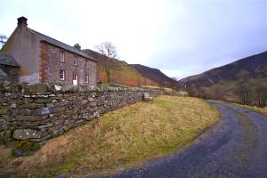 an old stone wall next to a stone house at The Dash Farmhouse in Bassenthwaite