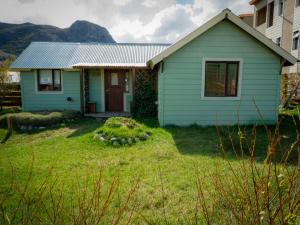 a small blue house with a grass yard at Casa al Río in El Chalten