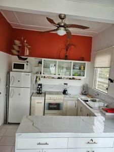 a kitchen with white appliances and a ceiling fan at VILLA SANTORO Casa playa de Castelnuovo-Atacames in Atacames