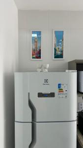 a white refrigerator in a kitchen with two pictures at Apartamento Terra Firme in Rio das Ostras