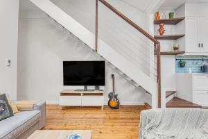 a living room with a television and a staircase at The Newtown Nest - Managed by X Hospitality in Sydney