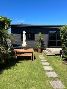 a house with a bench and an umbrella in the yard at Evolve Bach in Whitianga