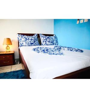 a bed with blue and white pillows and a blue wall at Fustelle city 2 in Douala