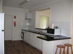 a kitchen with a counter with a microwave and two stools at Hayden House in Delegate