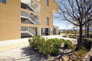 un edificio con un albero di fronte di Apparthotel Séjours & Affaires Manosque a Manosque