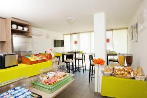 Apparthotel Séjours & Affaires Manosque في مانوسك: مطبخ ذو كونترات صفراء وطاولة مع كراسي