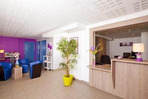 un hall avec un coin d'attente bleu et violet dans l'établissement Apparthotel Séjours & Affaires Manosque, à Manosque