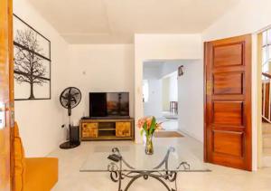 a living room with a television and a table at Eco Friendly Oasis Near Beaches and Waterfalls in Port Antonio