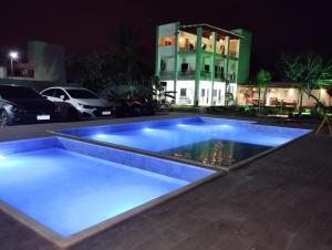 圣阿马鲁Eco House Gaivota - Cond Ville Portal das Dunas的大楼前的蓝色灯光游泳池