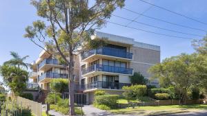 un edificio de apartamentos con balcones y un árbol en Portside No 9, en Nelson Bay