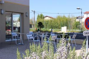 un patio con mesas y sillas frente a un edificio en The Originals Access,Tendance Hôtel, Saint-Etienne, en Andrézieux-Bouthéon