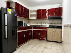 a kitchen with wooden cabinets and a black refrigerator at Hogar El Descanso Itagui in Itagüí