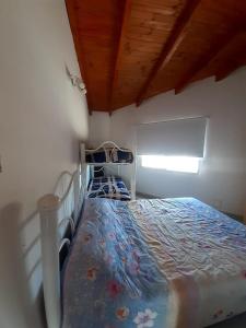 a bedroom with a bed with a comforter and a window at Gotas de Rocio in San Antonio Oeste