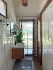 a bathroom with a sink and a large window at Phiratara River House บ้าน พิรธารา ริมแม่น้ำปราจีนบุรี in Ban Suan Phlu