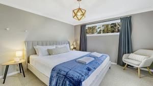 a bedroom with a bed and a chair and a window at Mount Gibraltar Retreat in Mittagong