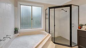 a bathroom with a tub and a shower and a window at Mount Gibraltar Retreat in Mittagong