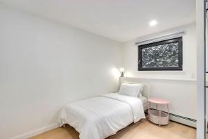 a white bedroom with a bed and a window at Classic King Size Guest Suite with AC in Burnaby