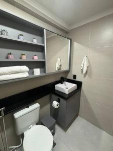 a bathroom with a white toilet and a sink at Flat Rosarinho - Confortável e Super Completo in Recife