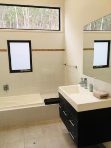 un bagno con vasca, lavandino e specchio di Architecturally Designed Rural Retreat a Forcett