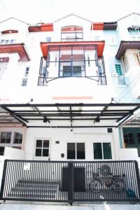 ein großes weißes Gebäude mit einem Tor davor in der Unterkunft Near BTS Bearing Skytrain- Homey living Townhome - 4 Bedrooms in Bangkok