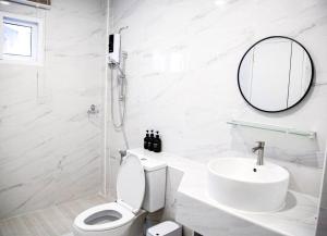 ein weißes Badezimmer mit Toilette und Waschbecken in der Unterkunft Near BTS Bearing Skytrain- Homey living Townhome - 4 Bedrooms in Bangkok + 25 Fotos