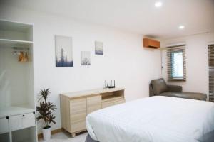 ein Schlafzimmer mit einem Bett, einem Schreibtisch und einem Stuhl in der Unterkunft Near BTS Bearing Skytrain- Homey living Townhome - 4 Bedrooms in Bangkok