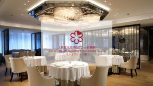 a restaurant with white tables and chairs and a chandelier at The Landis Taipei in Taipei