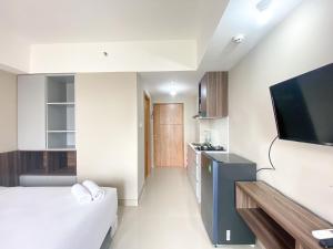 Cette chambre comprend un lit, une télévision et une cuisine. dans l'établissement Well Furnished and Cozy Studio at Gateway Park LRT City Jatibening Apartment By Travelio, à Bekasi