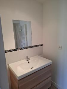 een badkamer met een witte wastafel en een spiegel bij Ateka Dax appartement in Dax