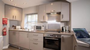 a kitchen with white cabinets and a laptop on the counter at Easy Reach in Ambleside +11 photos