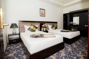 a hotel room with two beds and a mirror at Gallant Central Hotel Hai Phong in Hai Phong
