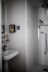 biała łazienka z prysznicem i umywalką w obiekcie Le Pigalle, a Member of Design Hotels w Paryżu