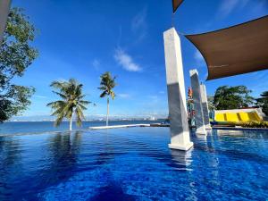 a pool with a view of the ocean and palm trees at Crusoe Cabins Costa Azalea in Davao City