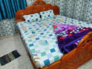 Una cama de madera con una colcha y almohadas encima. en Diya Homestay, en Santiniketan