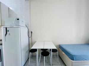 a small room with a table and a refrigerator and a bed at Itararé um sonho de mar in São Vicente