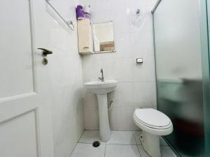 a white bathroom with a toilet and a sink at Itararé um sonho de mar in São Vicente +20 photos