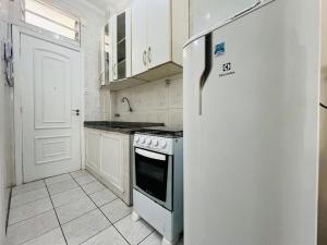a white kitchen with a refrigerator and a stove at Itararé um sonho de mar in São Vicente