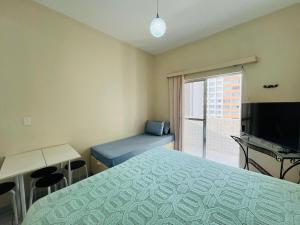a bedroom with a bed and a tv and a window at Itararé um sonho de mar in São Vicente